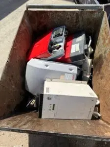 Car batteries and electrical units in a collection bin at the yard